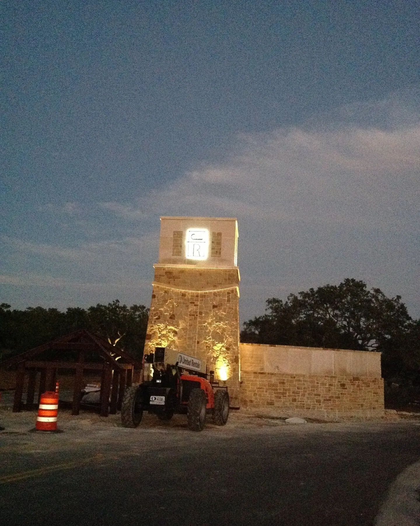 Lit stone tower entrance at dusk with a utility vehicle